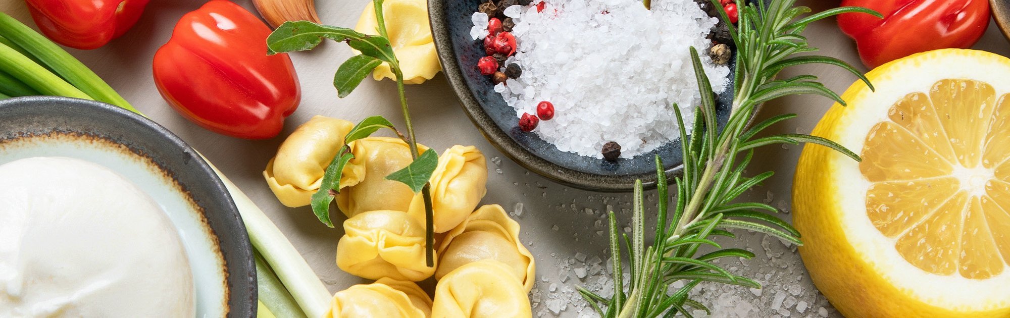 Slider Ernährung Frische Zutaten wie Paprika, Zitrone, Kräuter, Knoblauch auf einem Tisch