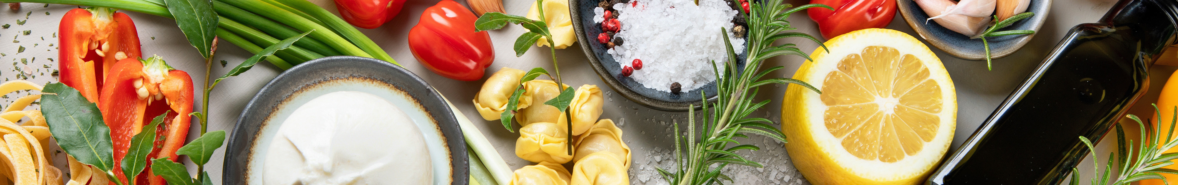 Slider Ernährung Frische Zutaten wie Paprika, Zitrone, Kräuter, Knoblauch auf einem Tisch